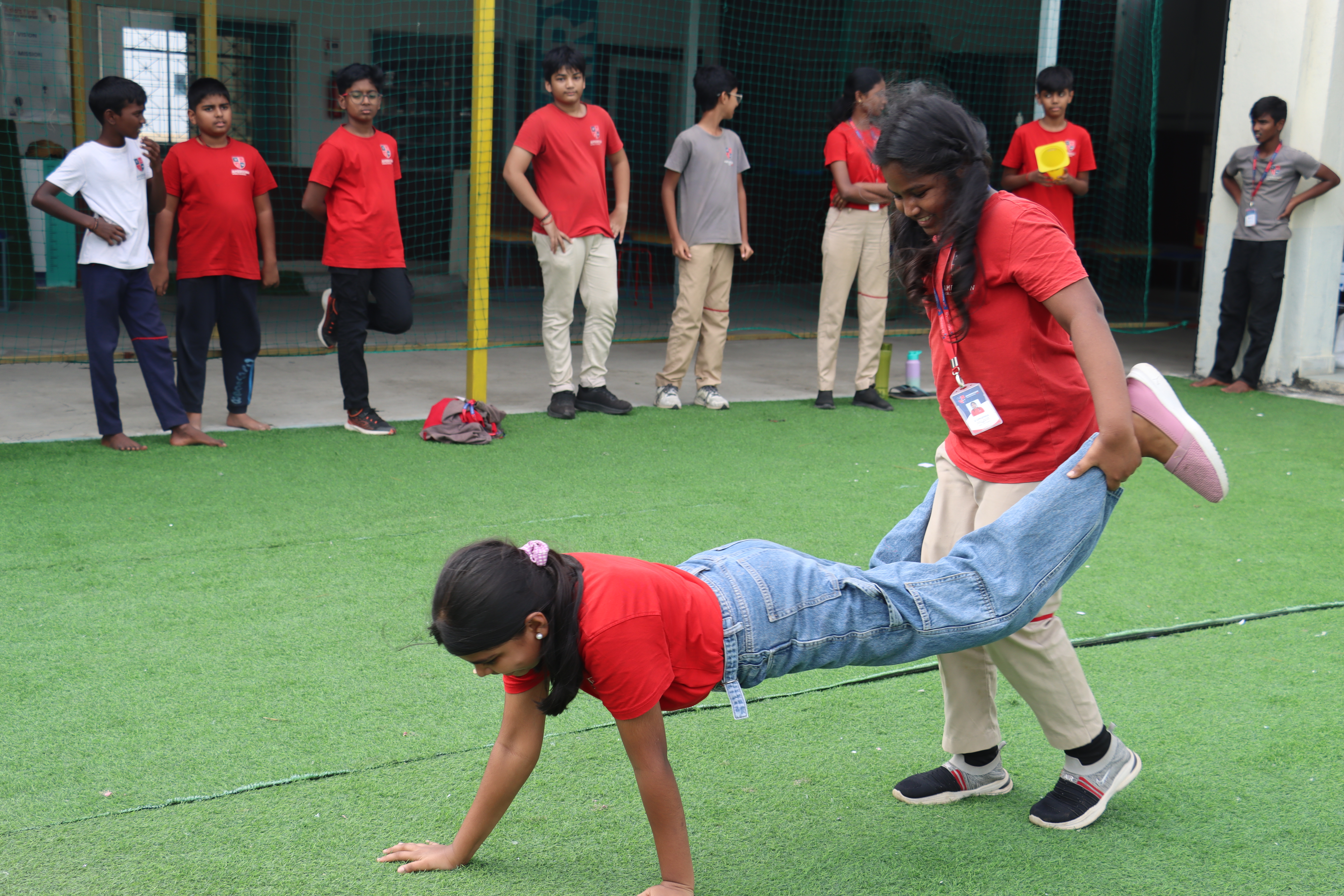 AWS older student helping a younger one with floor exercises during PE