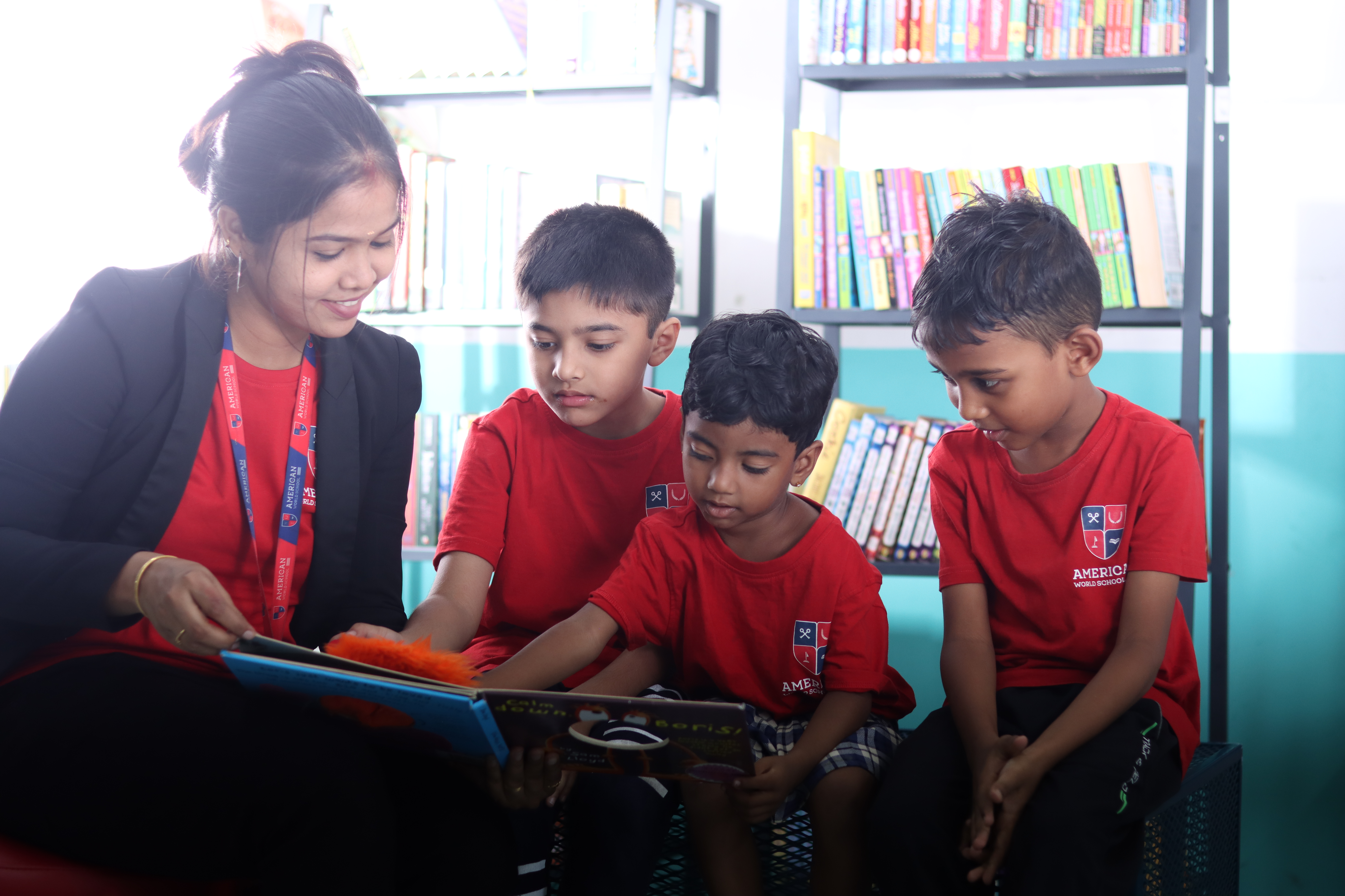 AWS teacher reading a picture book with three young boys on a bench