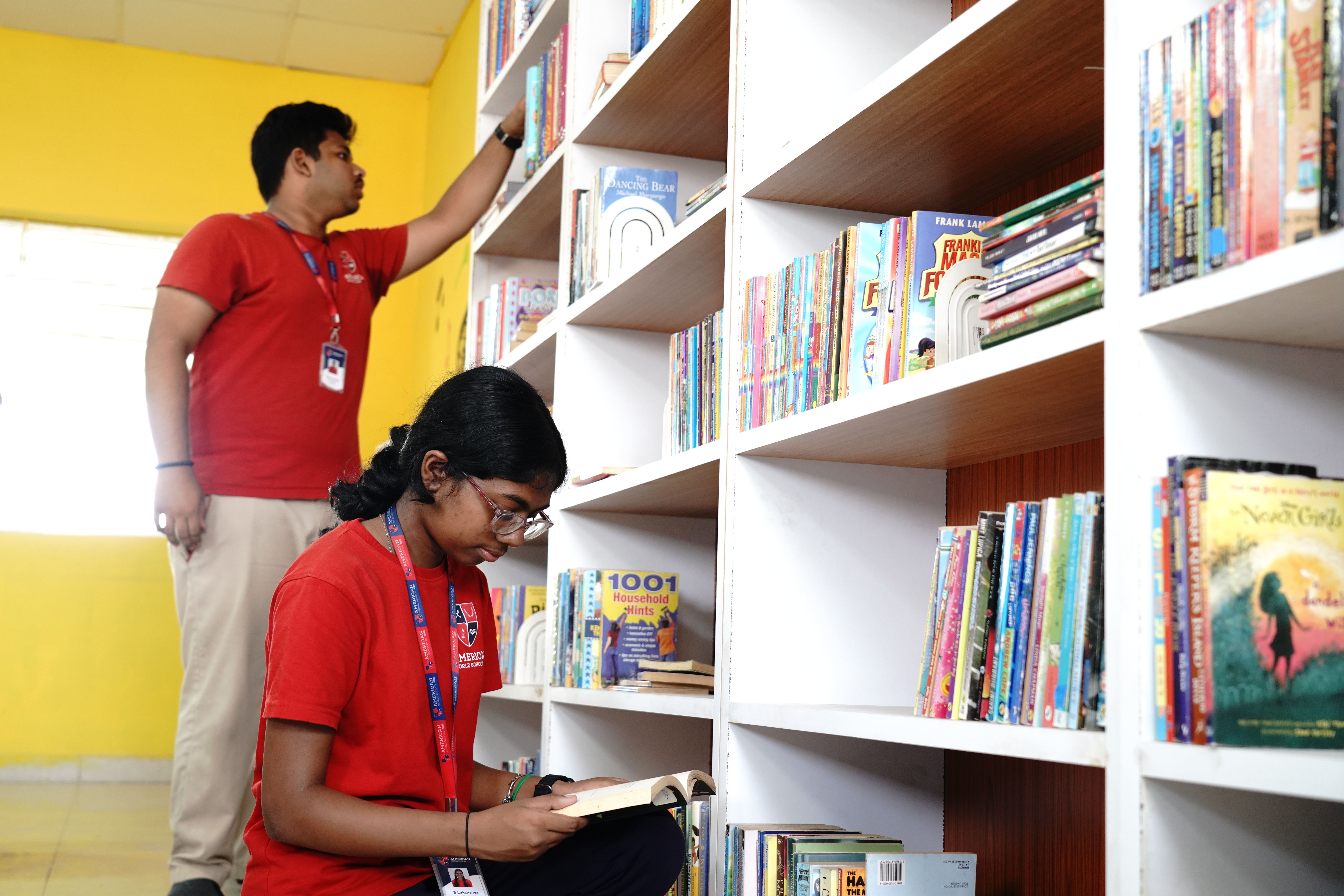 Older AWS student helping a younger student find a book